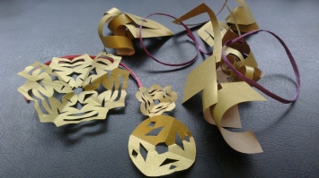 several snowflakes made out of gold paper, plus some scrap gold paper, plus a purple ribbon